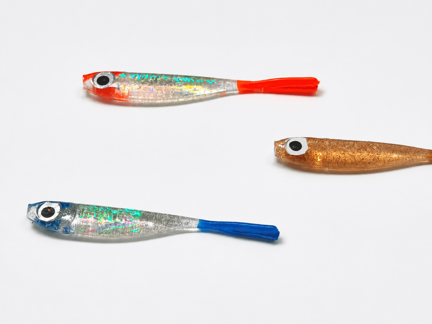 Três iscas soft modelo shad, cada uma com um esquema de cor diferente