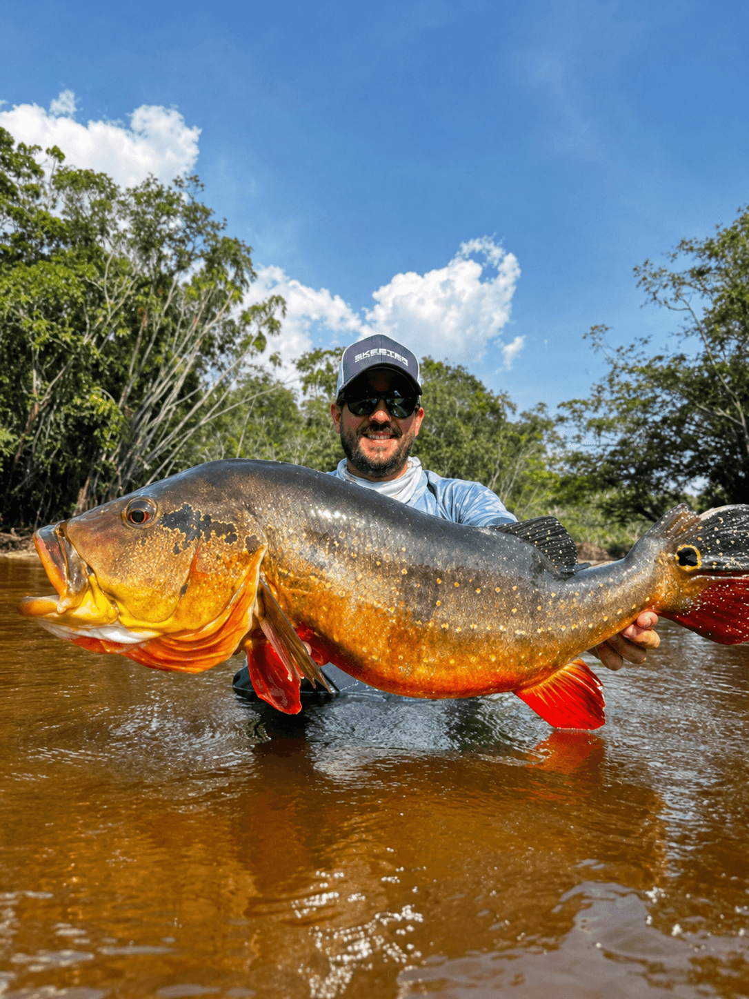 Pescador segurando um tucunaré fisgado durante teste de campo